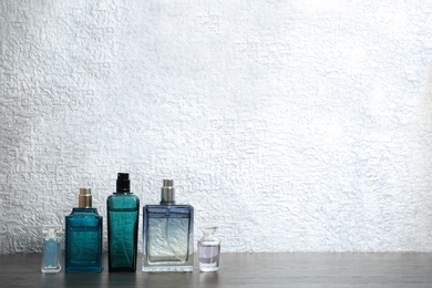 Different perfume bottles on table against color background