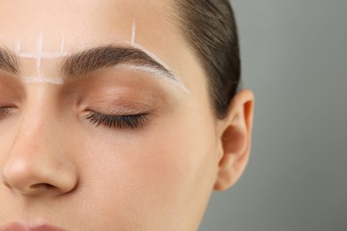 Photo of Eyebrow correction. Young woman with markings on face against grey background, closeup. Space for text