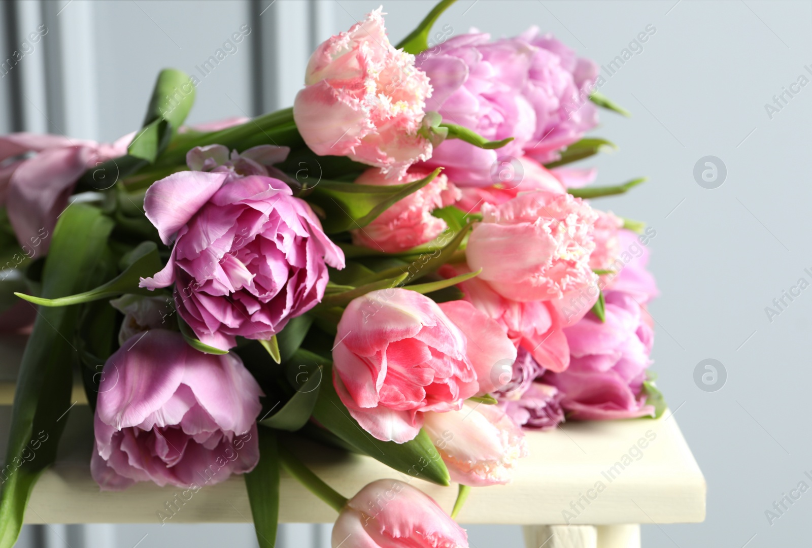 Photo of Beautiful bouquet of colorful tulip flowers on stool