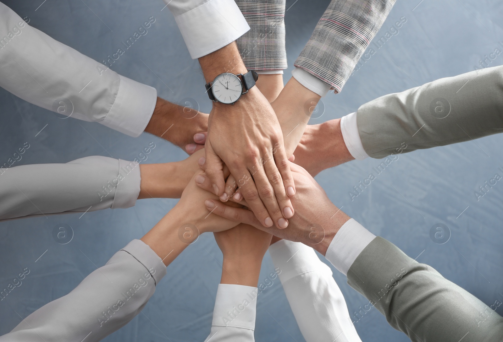 People holding hands together over grey stone background, top view. Unity concept Photo of People holding hands together over grey stone background, top view. Unity concept