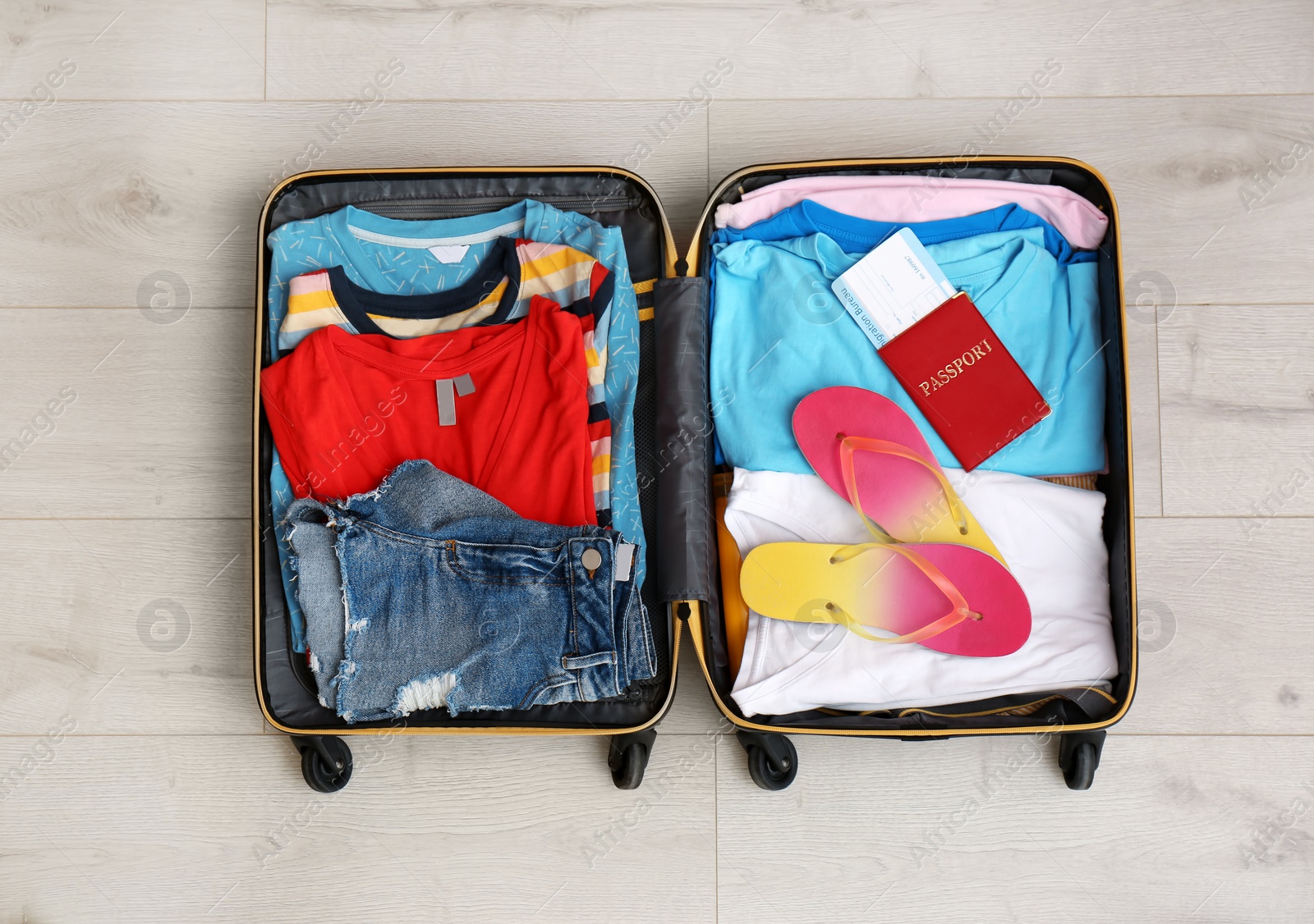 Photo of Packed suitcase with summer clothes and passport on wooden background, top view