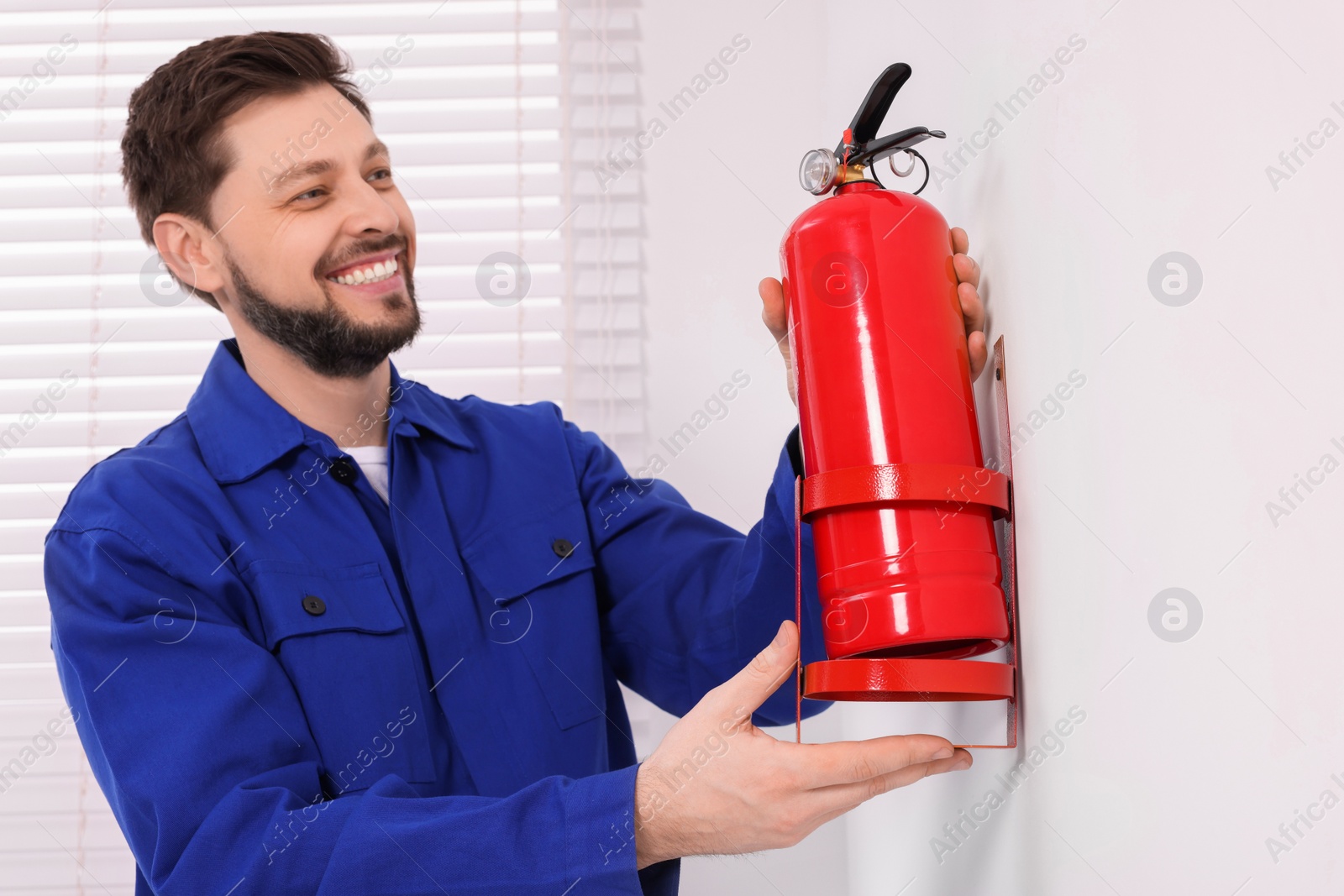 Photo of Man checking fire extinguisher indoors, selective focus