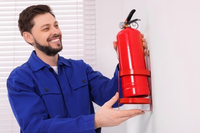 Photo of Man checking fire extinguisher indoors, selective focus