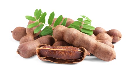 Photo of Delicious ripe tamarinds with leaves on white background. Exotic fruit