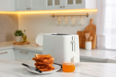 Breakfast served in kitchen. Toaster, crunchy bread and honey on white marble table