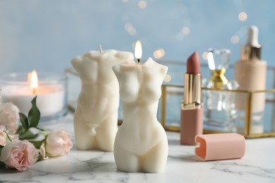 Photo of Beautiful male and female body shaped candles on white marble table