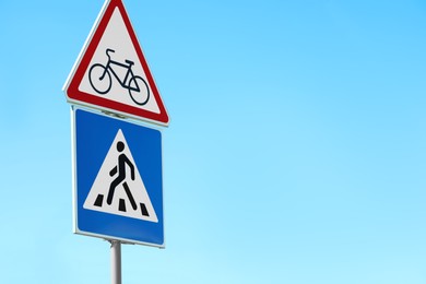 Photo of Post with Pedestrian Crossing and No Bikes traffic signs against blue sky on sunny day