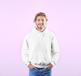 Portrait of man in hoodie sweater on color background. Space for design