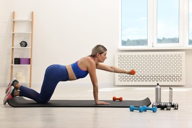 Online fitness trainer. Woman doing exercise with dumbbells near laptop at home