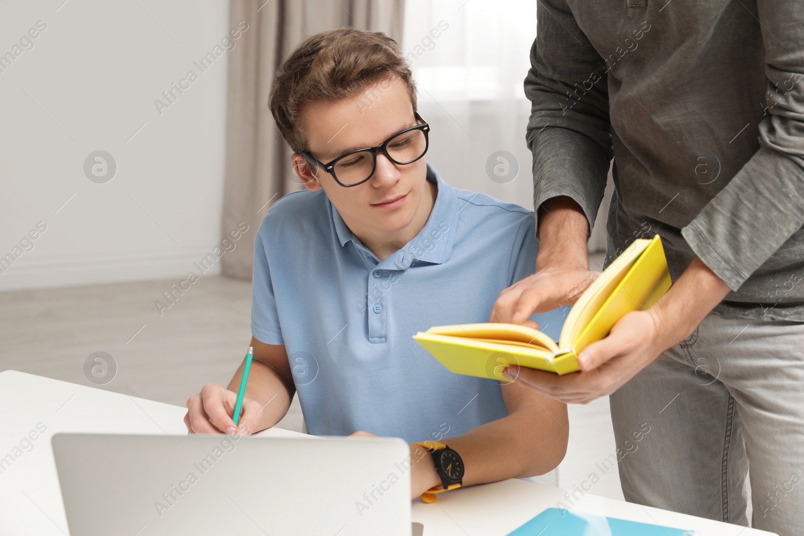 Photo of Father helping his teenager son with homework indoors