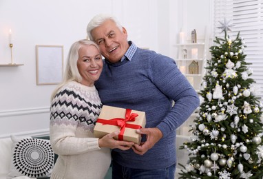 Happy mature couple with gift box at home. Christmas celebration