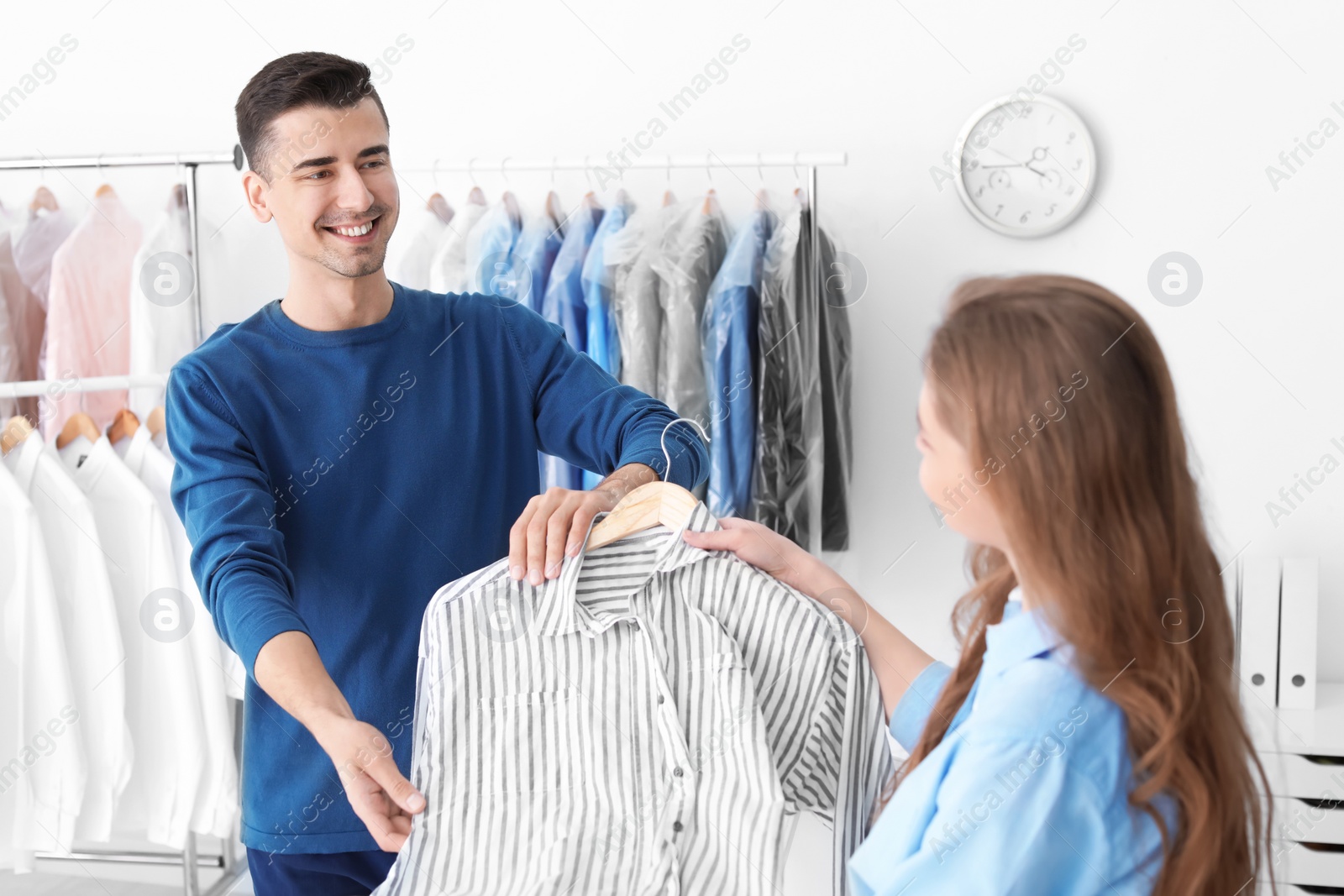 Photo of Young woman giving shirt to dry-cleaner's worker