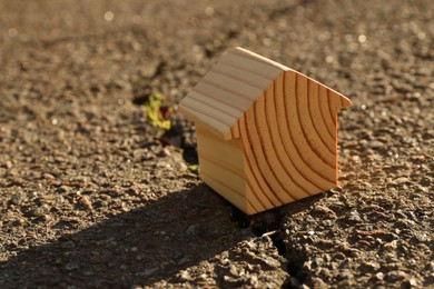 Photo of Wooden house model on cracked asphalt. Earthquake disaster