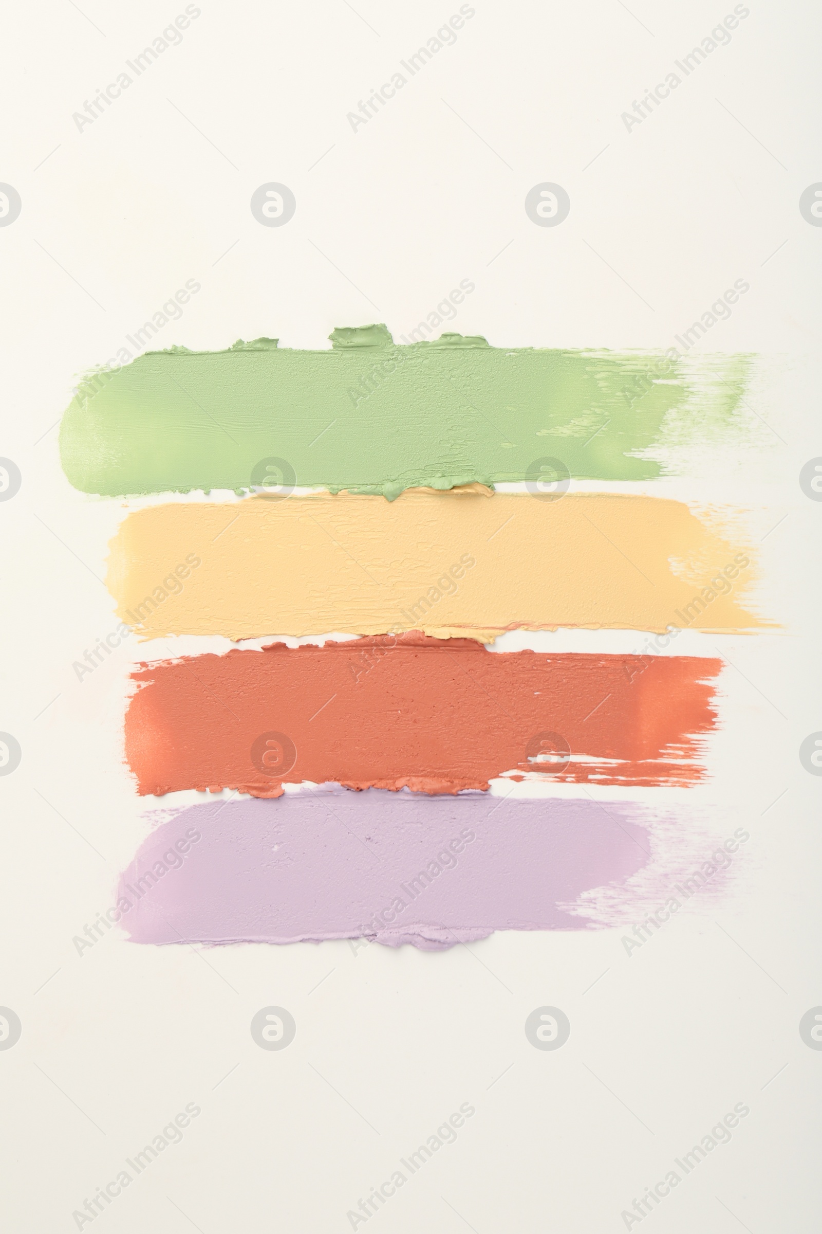 Photo of Samples of different color correcting concealers on white background, top view