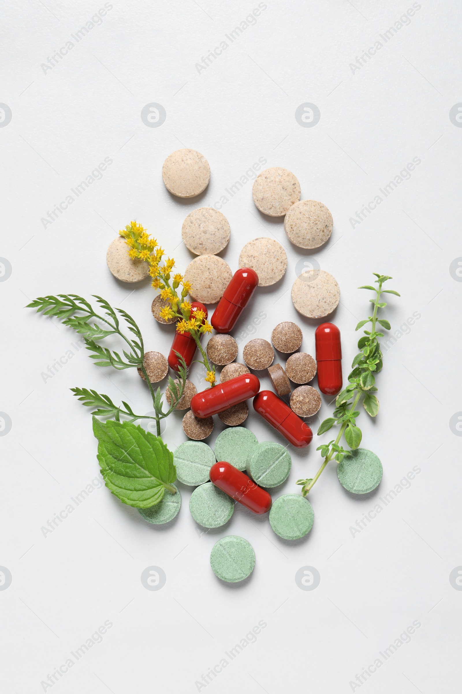 Photo of Different pills and herbs on white table, flat lay. Dietary supplements