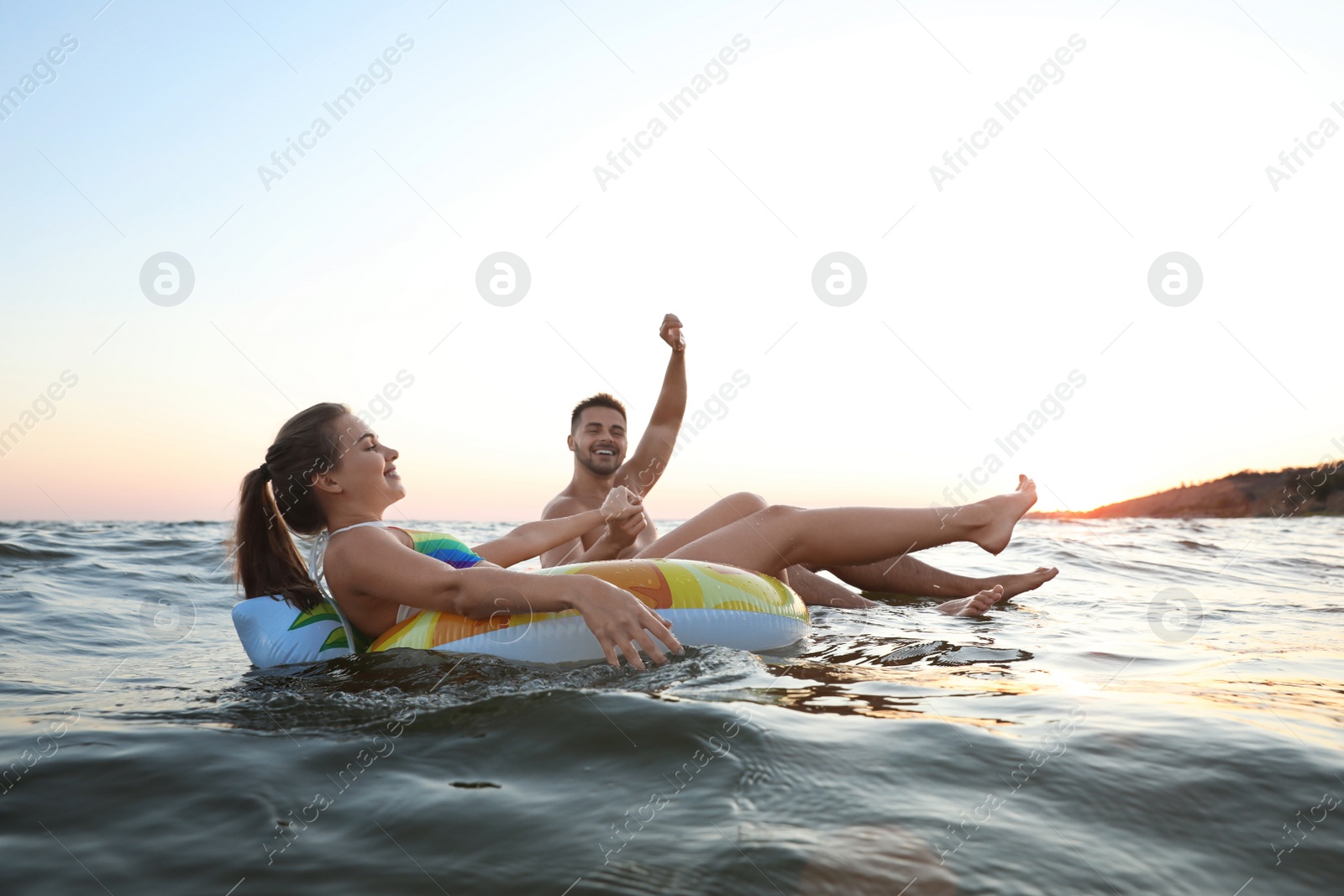 Photo of Happy young couple on inflatable rings in water