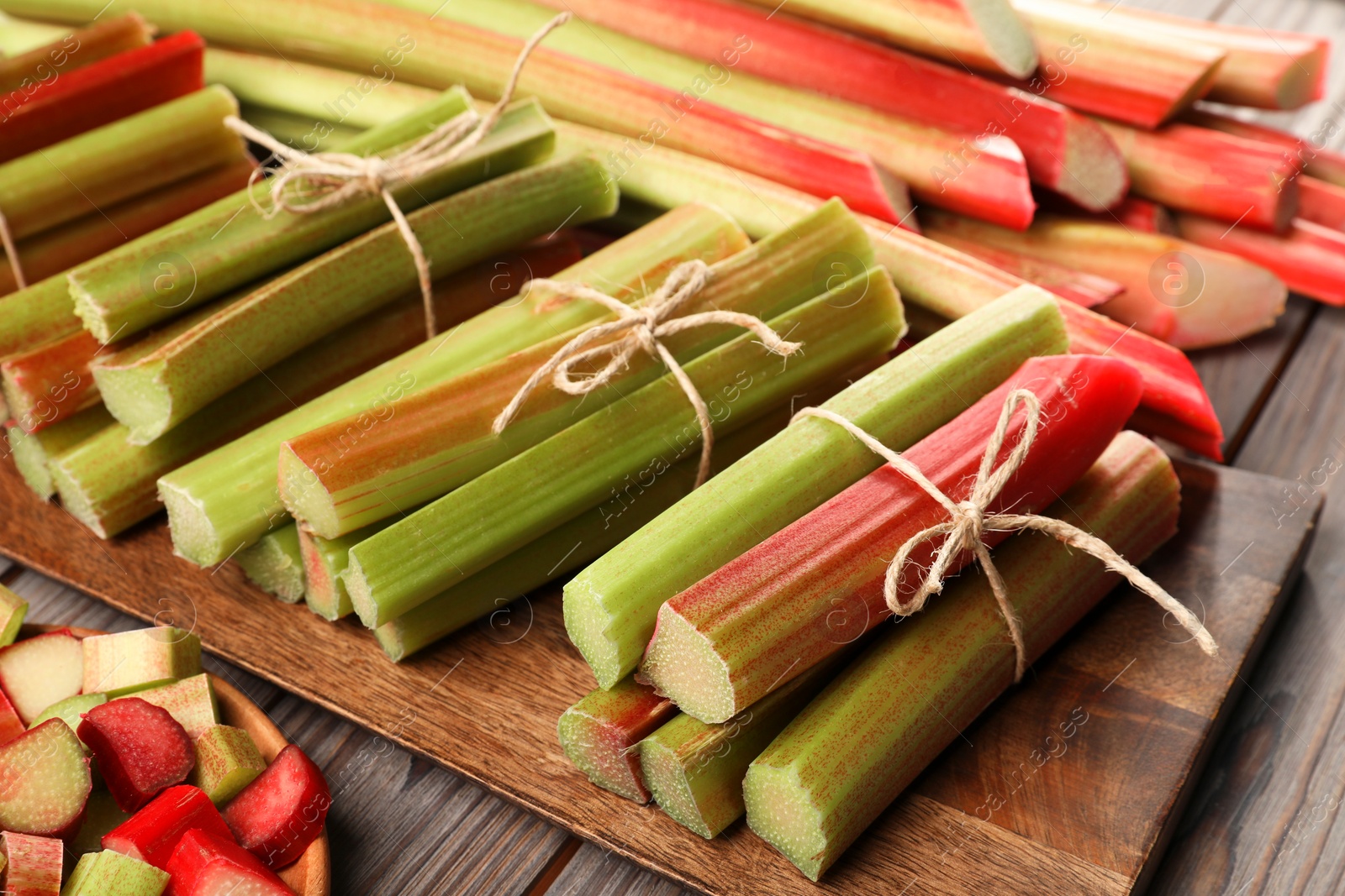 Photo of Many cut rhubarb stalks on wooden table, closeup