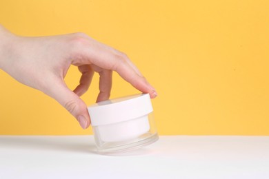 Photo of Woman with jar of cream on yellow background, closeup