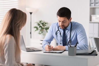 Professional doctor working with patient at white table in hospital