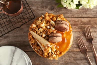 Photo of Delicious homemade cake with caramel sauce and popcorn on table, top view