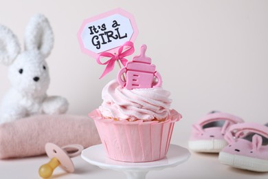 Photo of Beautifully decorated baby shower cupcake for girl with cream and topper on light background