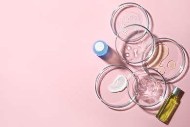 Photo of Many Petri dishes and cosmetic products on pink background, flat lay. Space for text