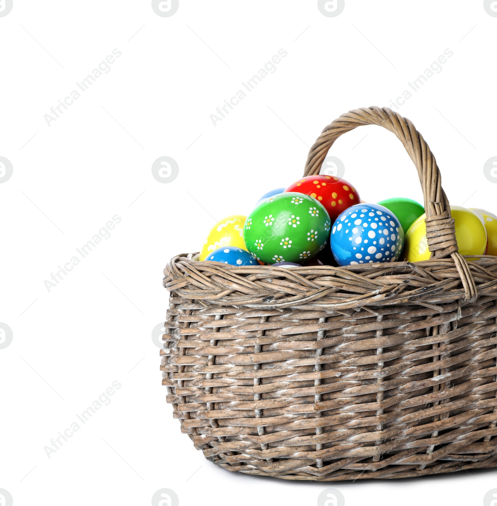 Photo of Decorated Easter eggs in wicker basket on white background