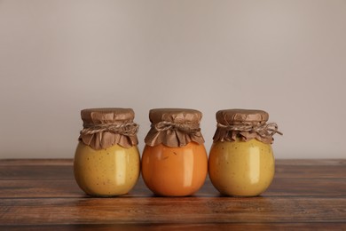 Photo of Jars with preserved fruit jams on wooden table