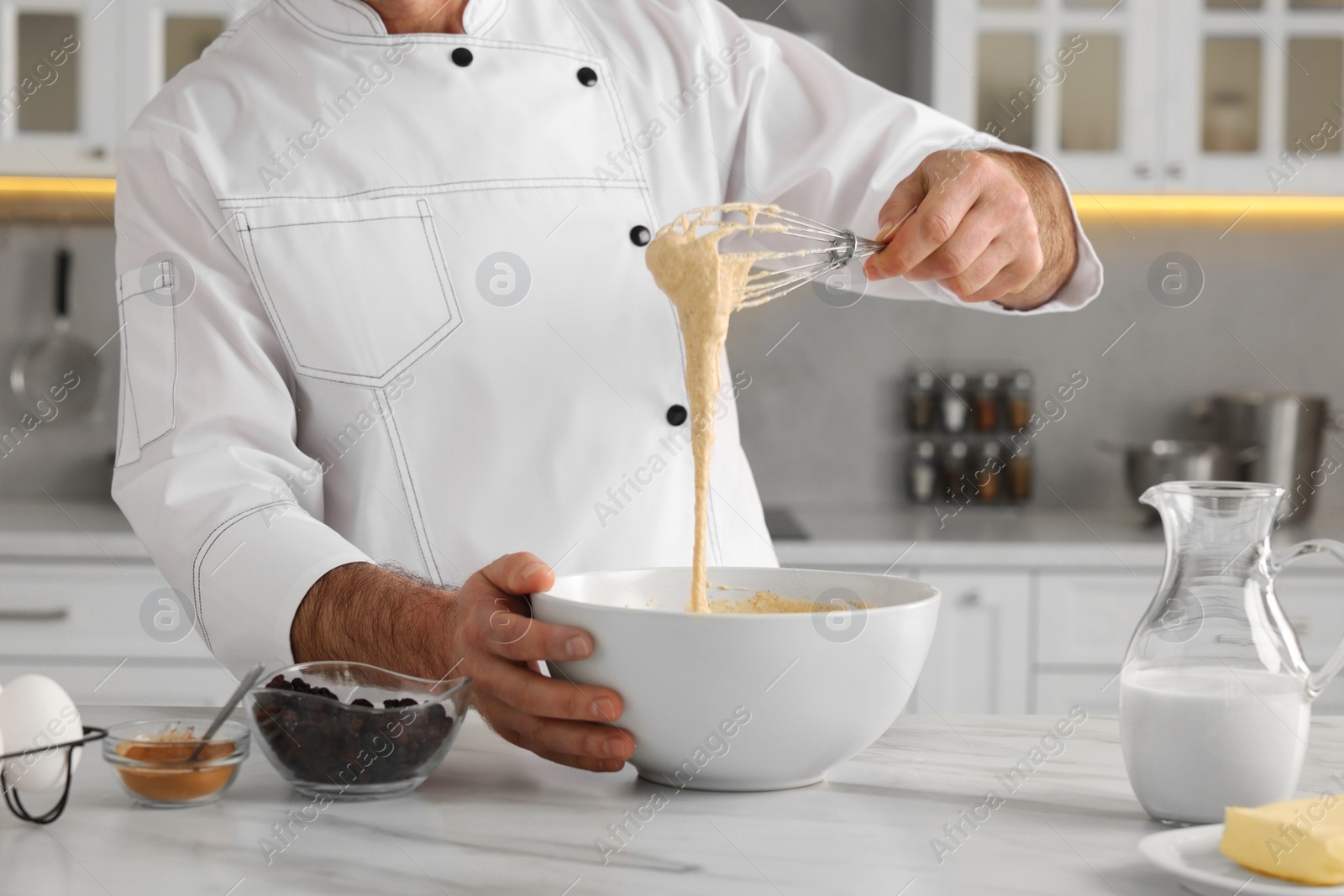 Photo of Professional chef making dough at white marble table indoors, closeup