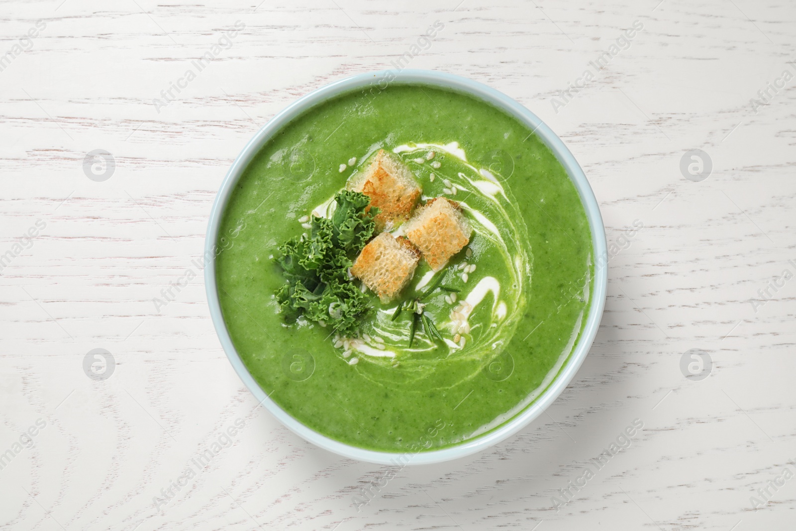 Photo of Tasty kale soup on white wooden table, top view