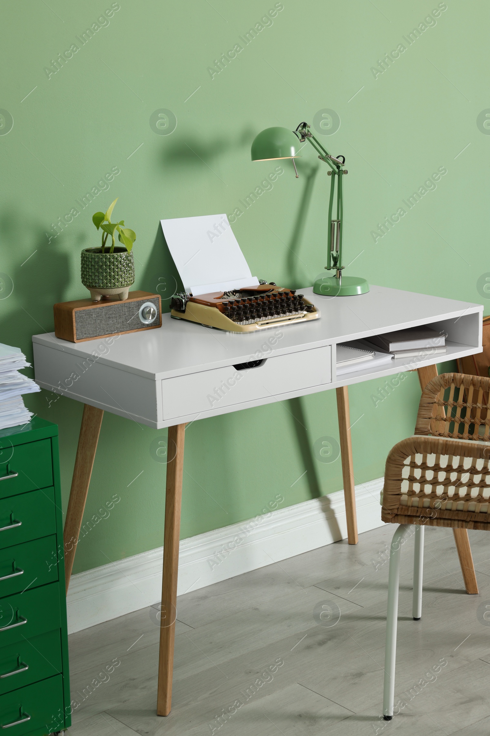 Photo of Writer's workplace with typewriter on wooden desk near pale green wall in room