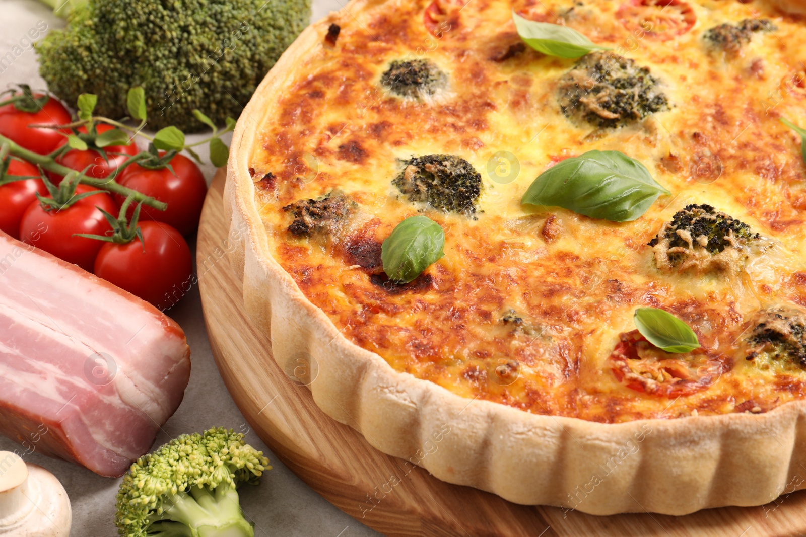 Photo of Delicious homemade quiche and ingredients on table, closeup