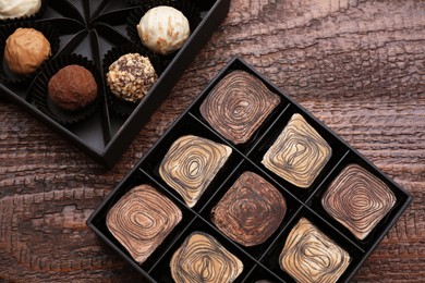 Photo of Boxes of tasty chocolate candies on wooden table, flat lay