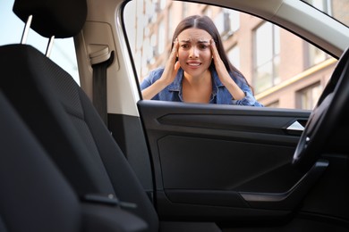 Photo of Automobile lockout, key forgotten inside. Emotional woman looking through car window