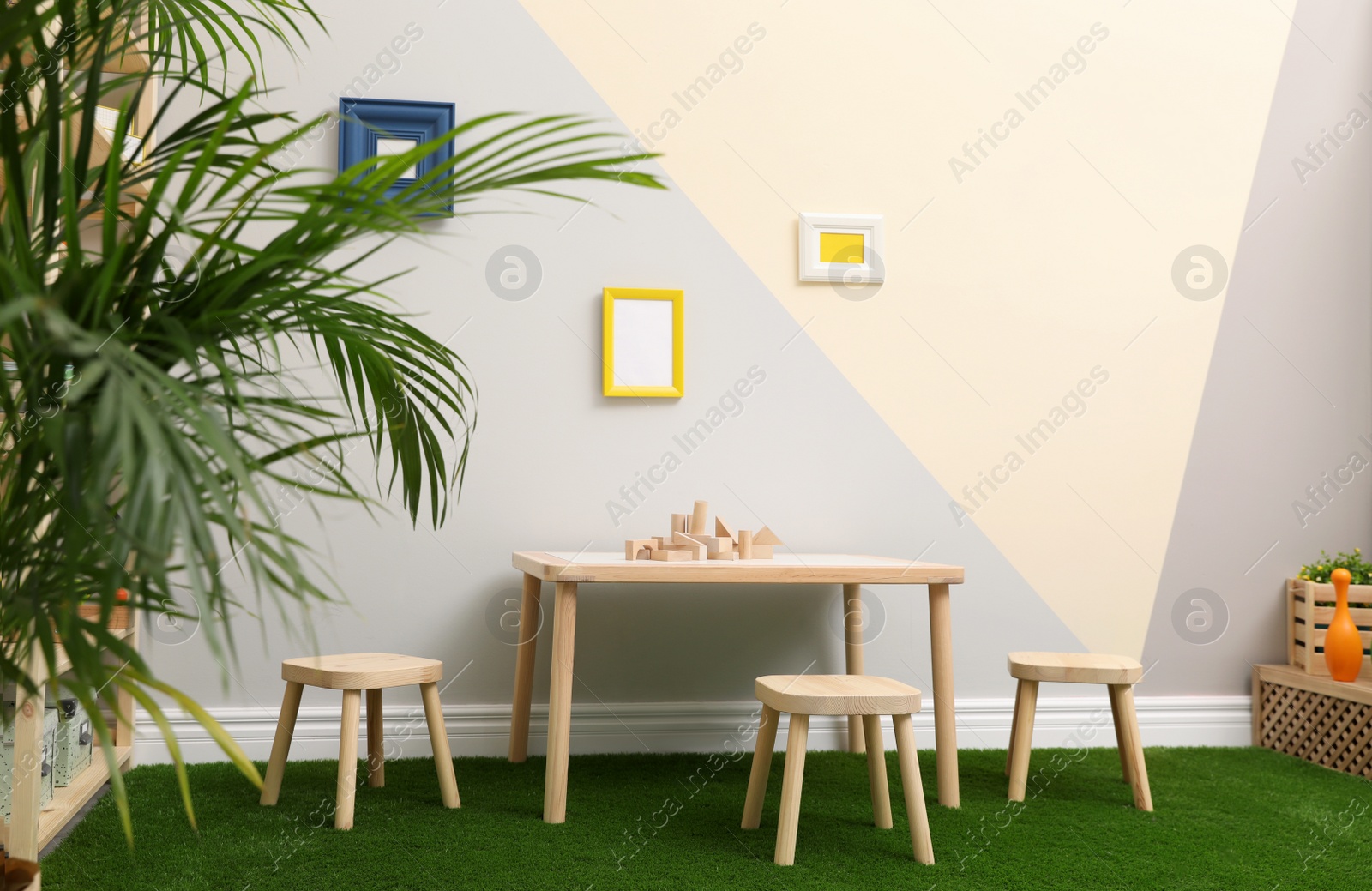 Photo of Stylish playroom interior with table, stools and green carpet