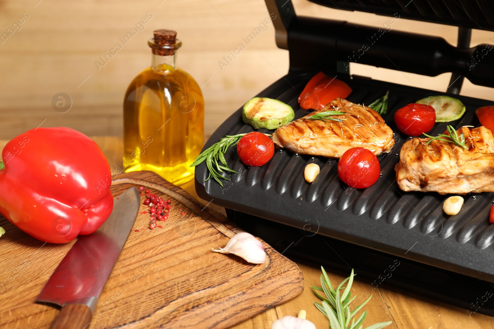 Photo of Electric grill with different products and knife on table