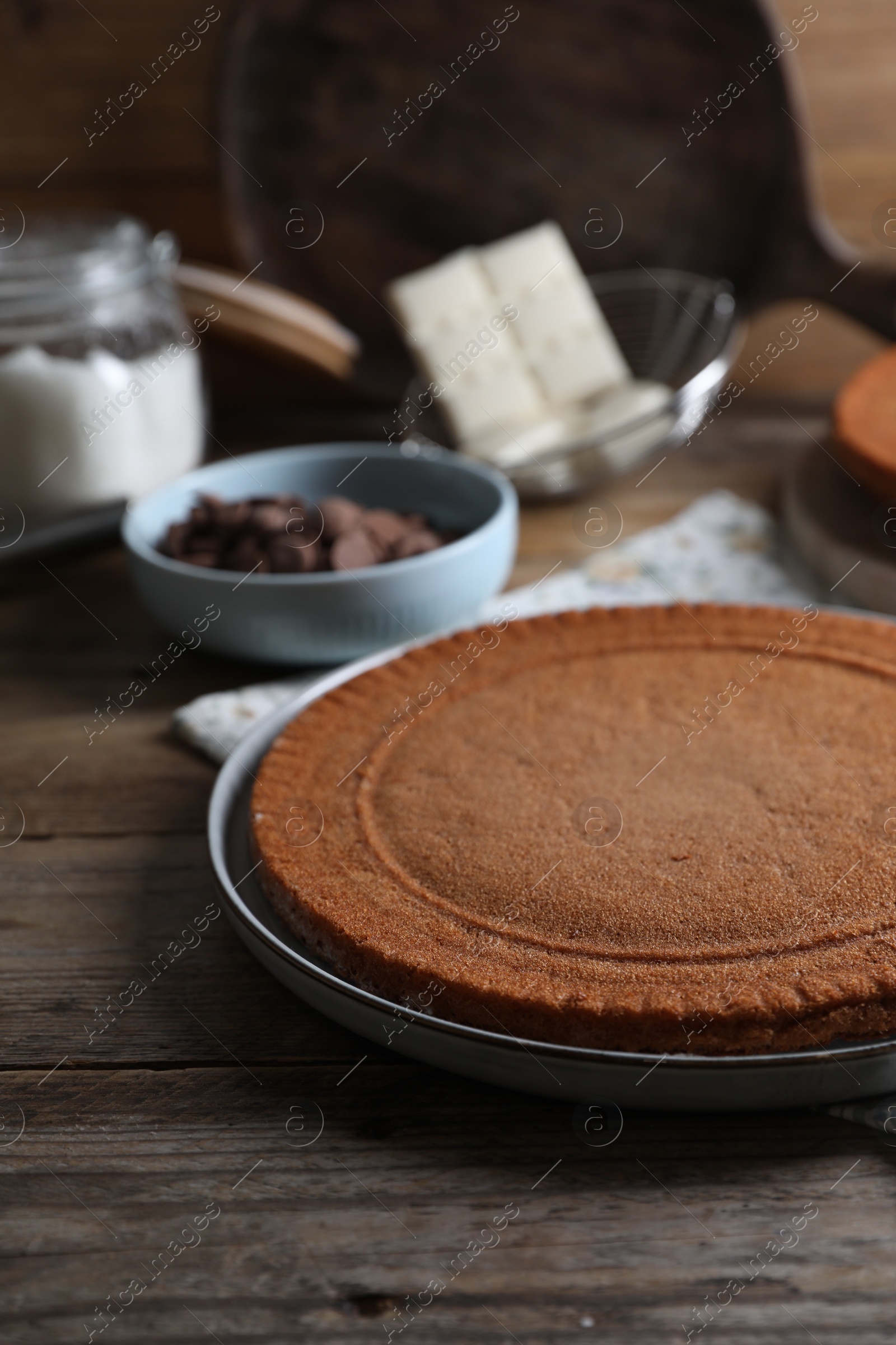 Photo of Delicious homemade sponge cake and ingredients on wooden table, closeup