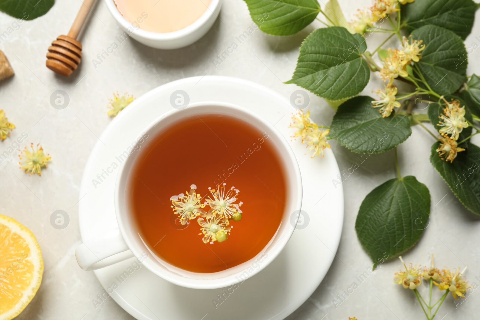 Photo of Flat lay composition with tasty tea and linden blossom on light grey marble table