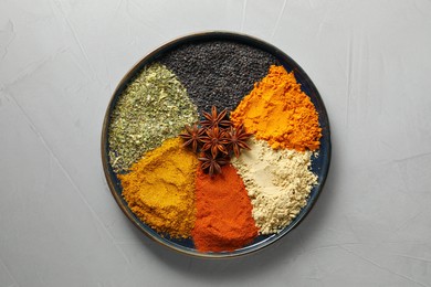 Photo of Plate with different spices on light grey table, top view