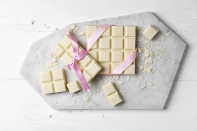 Photo of Tasty white chocolate on wooden table, flat lay