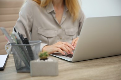 Photo of Young woman working with laptop at table, closeup