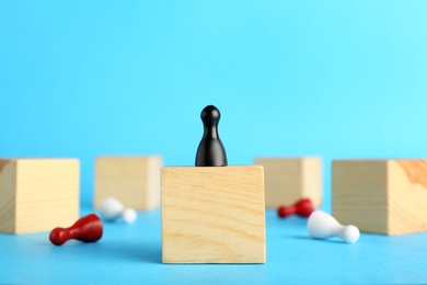 Photo of Board game pawn on top of wooden cube with other ones fallen against color background