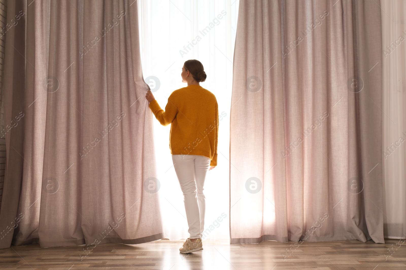 Photo of Woman near window with beautiful curtains at home in morning
