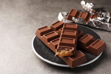 Plate with tasty chocolate bars on grey table, space for text