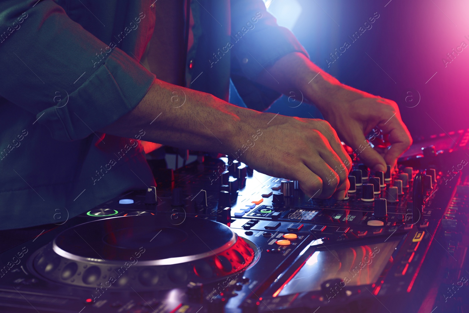 Photo of DJ creating music on modern console mixer in night club, closeup