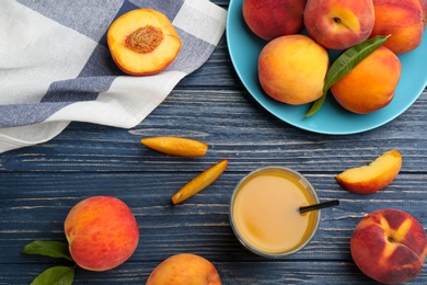 Photo of Natural peach juice and fresh fruits on blue wooden table, flat lay
