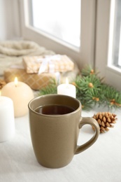 Composition with cup of hot winter drink near window. Cozy season