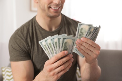 Photo of Young man counting money on blurred  background, closeup