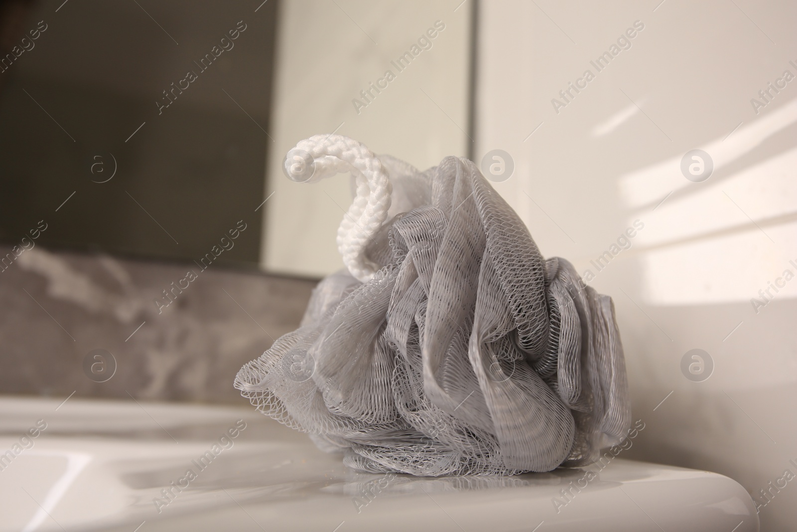 Photo of Grey shower puff on washbasin in bathroom, closeup