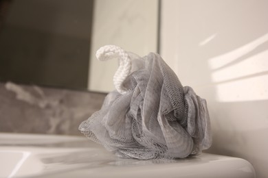 Photo of Grey shower puff on washbasin in bathroom, closeup